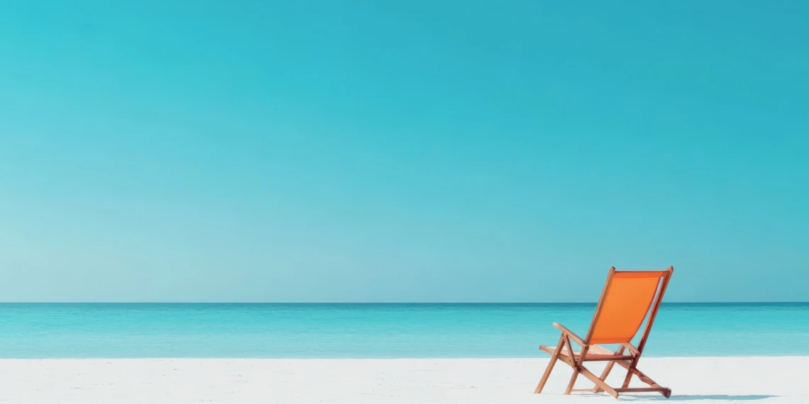 View of a white sand beach with an orange beach chair facing the ocean.